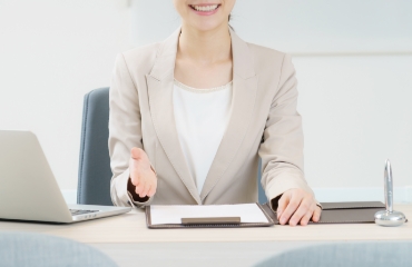 이빨을 보이며 무언가를 소개하는 듯한 손짓을 하고 있는 여자 사진